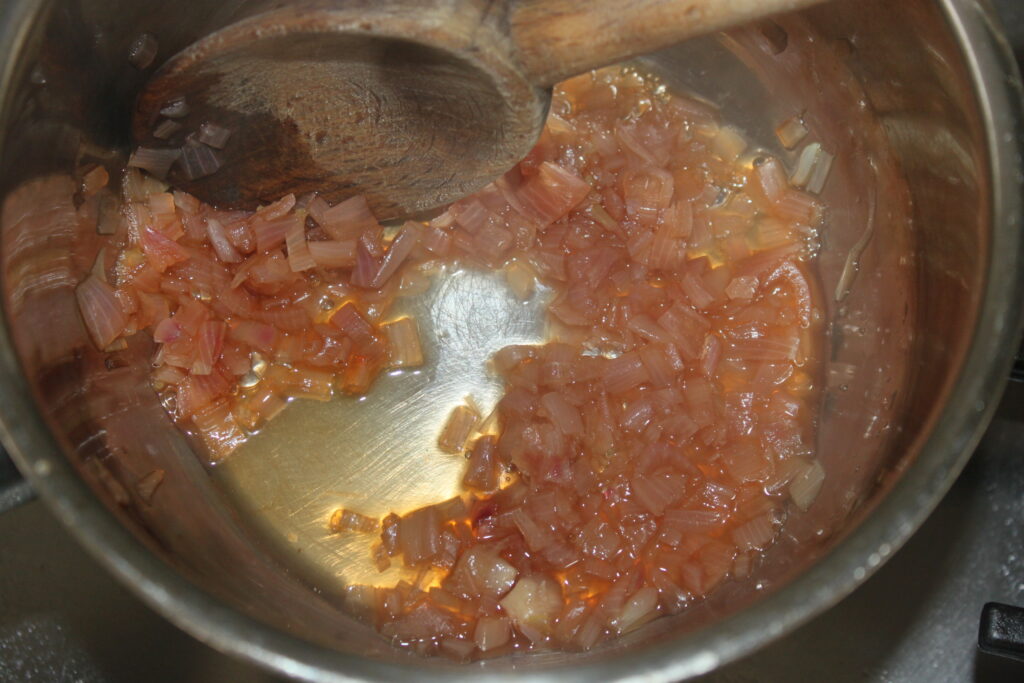 Les oignons coupés en dés sont sautés dans une casserole avec une cuillère en bois en les remuant, préparant ainsi la base d'une délicieuse sauce au beurre blanc.