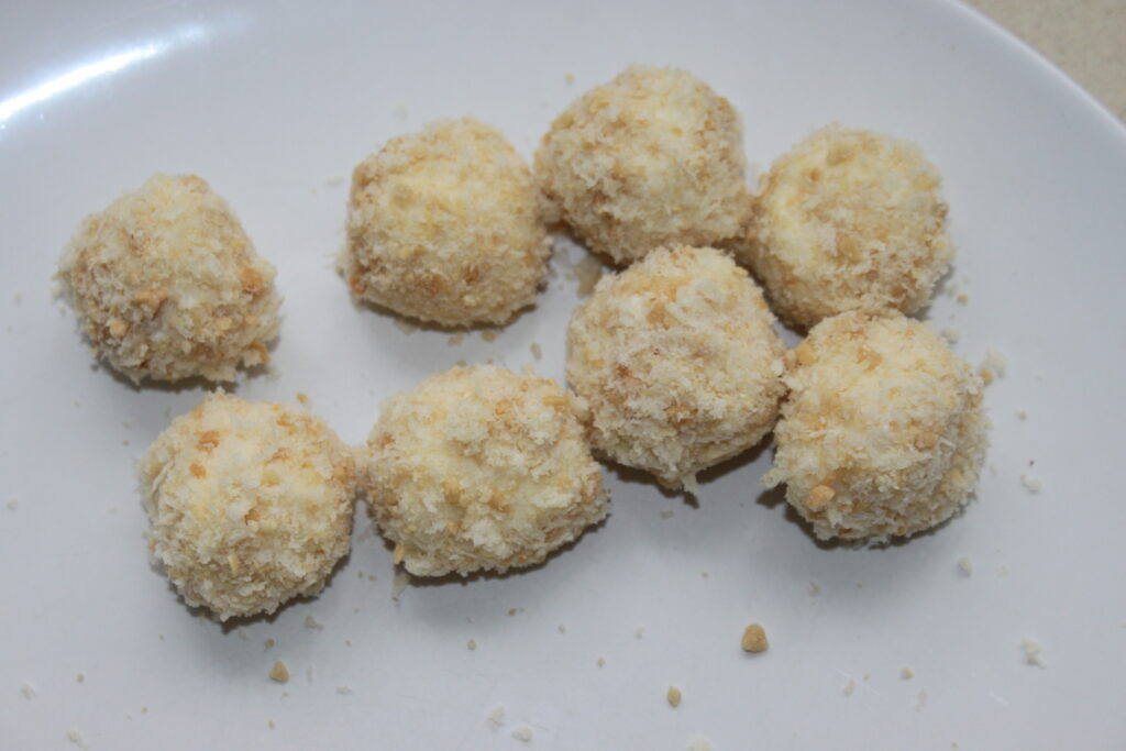 Huit boules de Mozza panées et frites disposées sur une assiette blanche, parfaitement complétées par un accompagnement de mayonnaise au wasabi.
