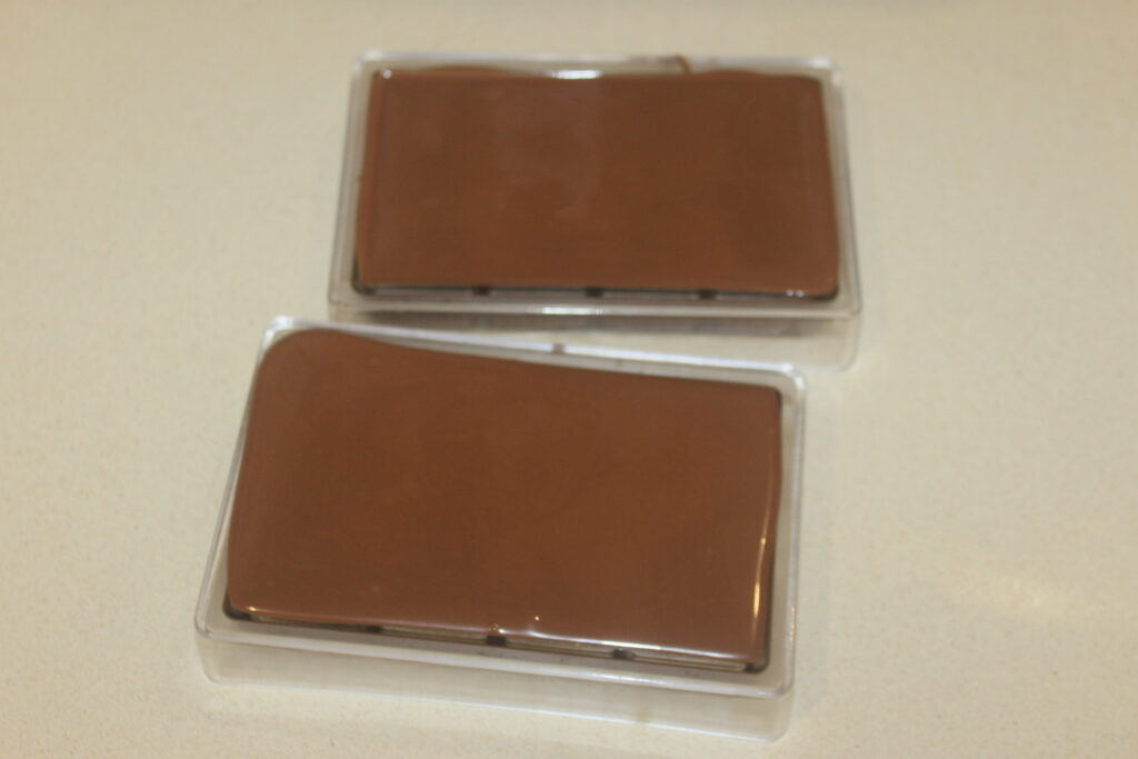 Deux barres rectangulaires de Chocolat de Dubaï dans des moules en plastique sont placées sur une surface de couleur claire.