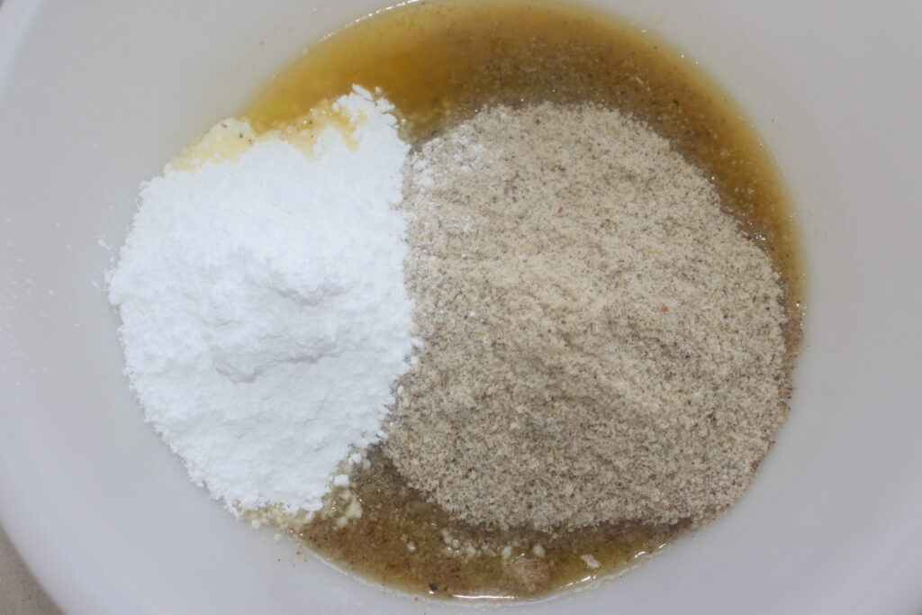 Un bol à mélanger contient du sucre cristallisé, de la cassonade et des blancs d'œufs prêts à être mélangés pour obtenir une pâte financière délicate.