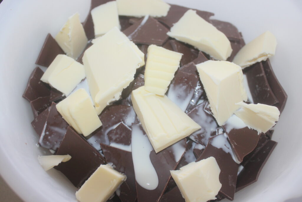 Des morceaux de chocolat noir et blanc hachés mélangés à du lait crémeux créent la base parfaite pour une tarte au chocolat décadente, le tout niché dans un bol blanc immaculé.