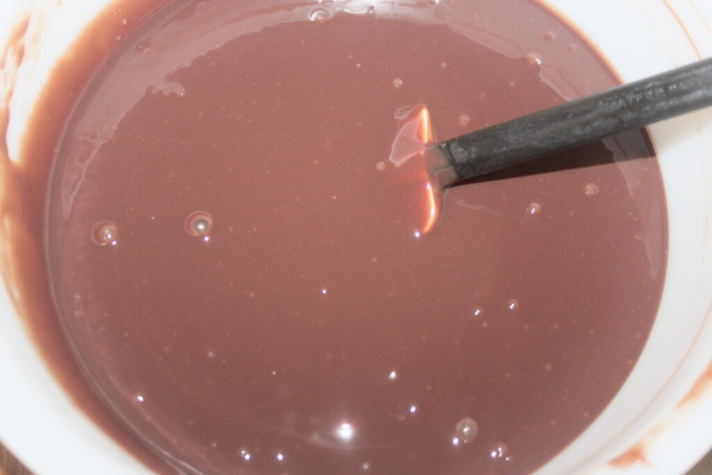 Un bol rempli de délicieux chocolat liquide remué avec une cuillère noire.