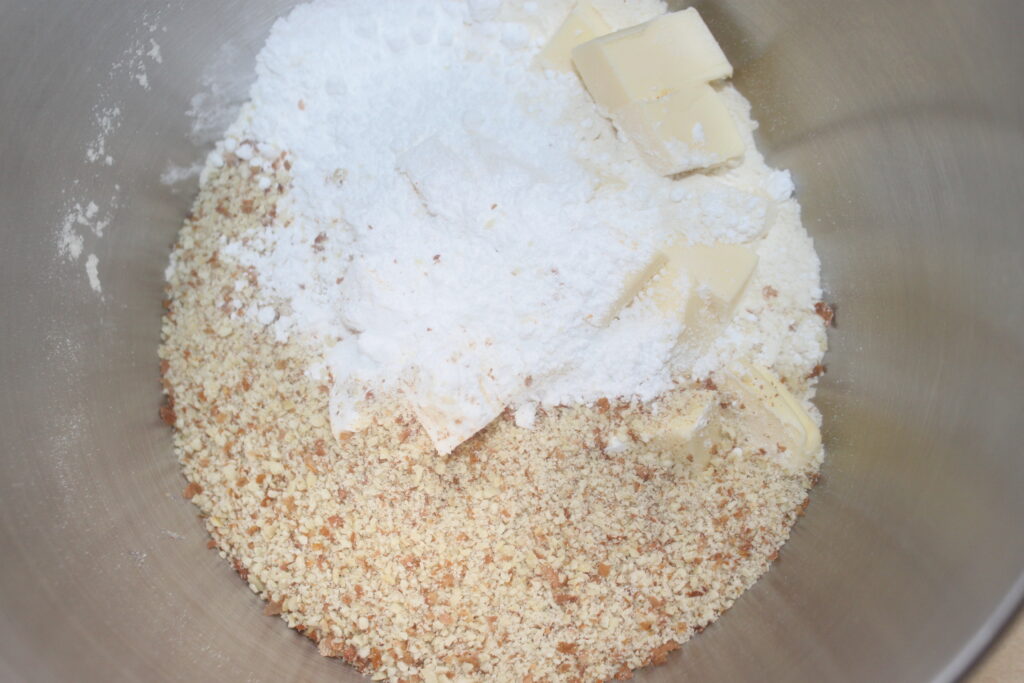 Dans un bol à mélanger, des ingrédients comme la chapelure, la farine et les morceaux de beurre se réunissent pour former la base parfaite pour une délicieuse tarte au chocolat.