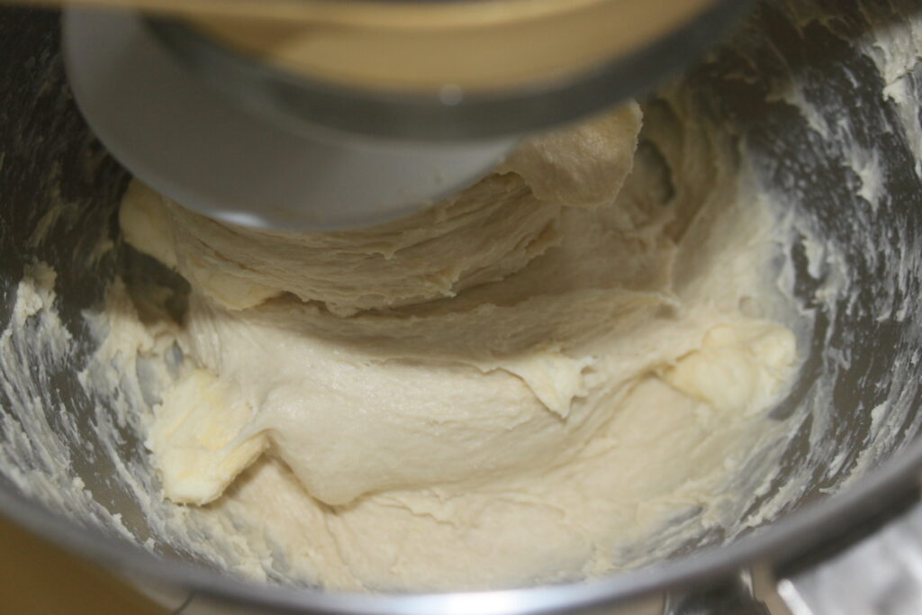 Le batteur sur socle tourne rythmiquement tandis qu'il transforme les ingrédients en une pâte lisse et moelleuse, prête à être façonnée en délicieux petits pains.