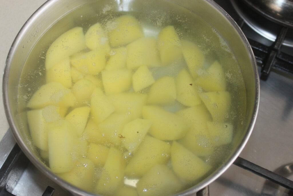 Des pommes de terre coupées en dés mijotant dans une casserole d'eau sur la cuisinière, bientôt transformées en une purée crémeuse, se marient parfaitement avec des petits pains moelleux pour un repas réconfortant par excellence.