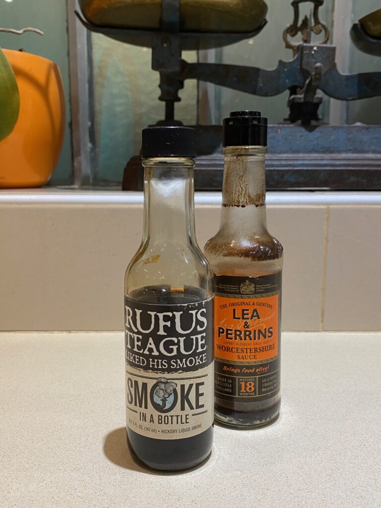 Deux bouteilles de sauce sur un comptoir ; l'une est la Smoke in a Bottle de Rufus Teague, et l'autre est la sauce Worcestershire de Lea & Perrins.