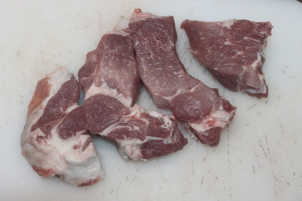 Morceaux de viande rouge crue avec marbrure de graisse blanche sur une planche à découper blanche.