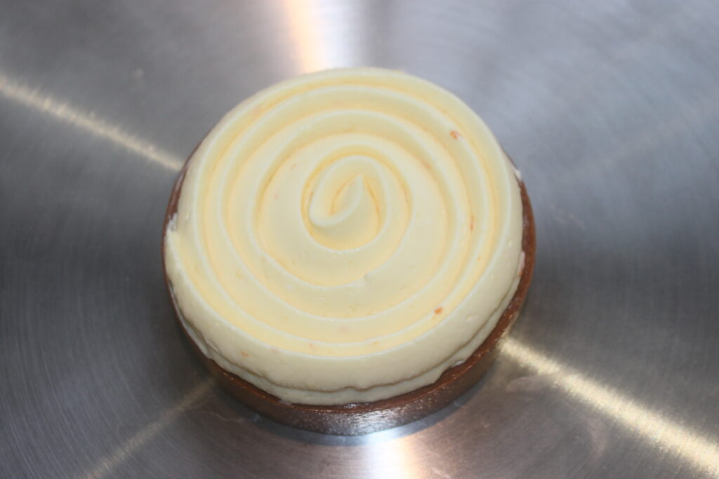 Les Tartelettes crème d'orange, dotées d'une croûte en chocolat et d'une spirale de garniture à la crème d'orange, reposent élégamment sur une surface métallique.