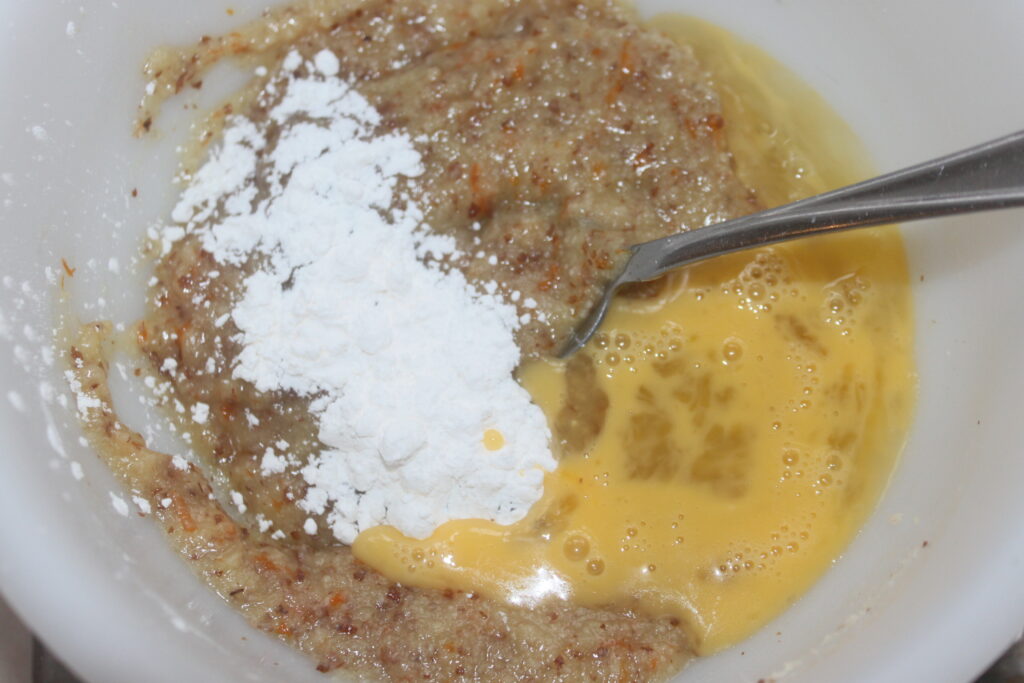 Un bol contenant des bananes écrasées, de la farine et des œufs battus est prêt à être mélangé. Ajoutez une touche d'originalité en incorporant des Tartelettes à la crème d'orange pour un délicieux arôme d'agrumes qui rehausse ce mélange simple.