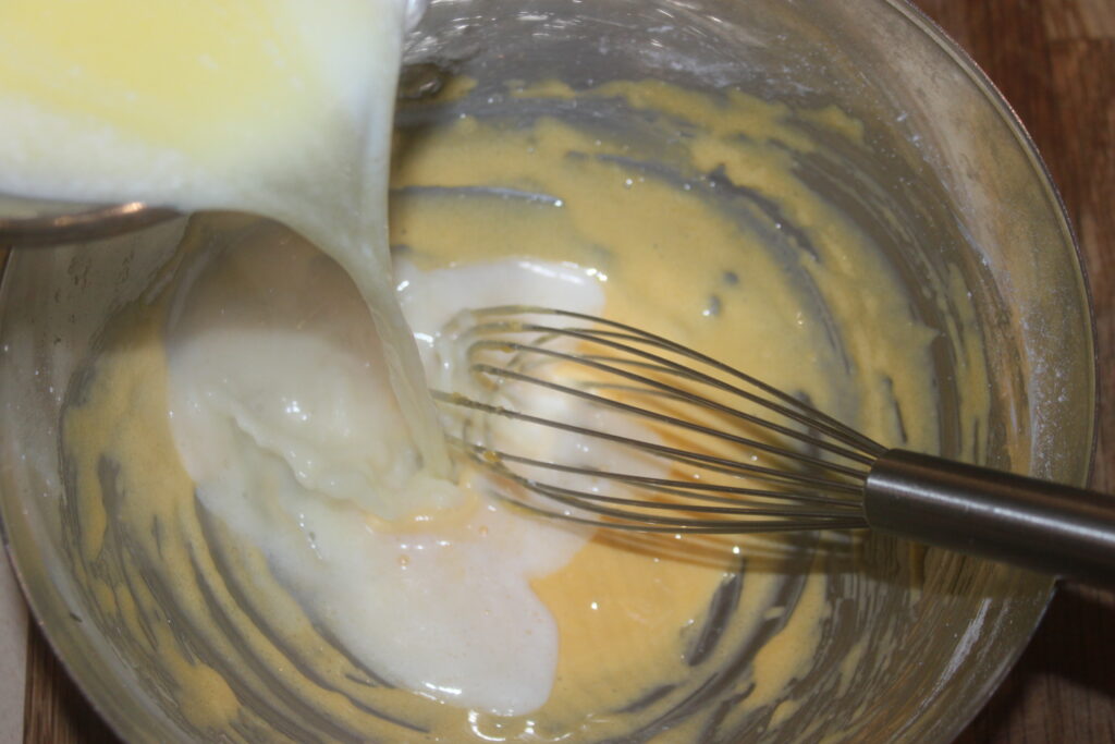 Le lait est versé dans un bol avec un fouet et de la pâte, prêt pour de délicieuses Tartelettes à la crème d'orange.
