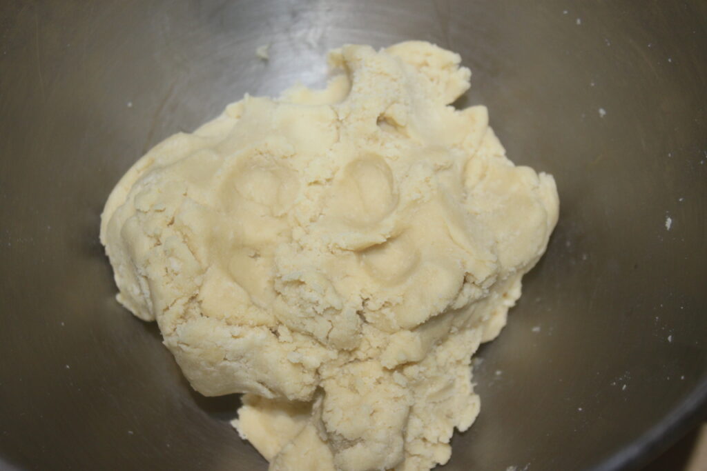 Une boule de pâte repose dans un saladier en métal, prête à réaliser de délicieuses Tartelettes à la crème d'orange.