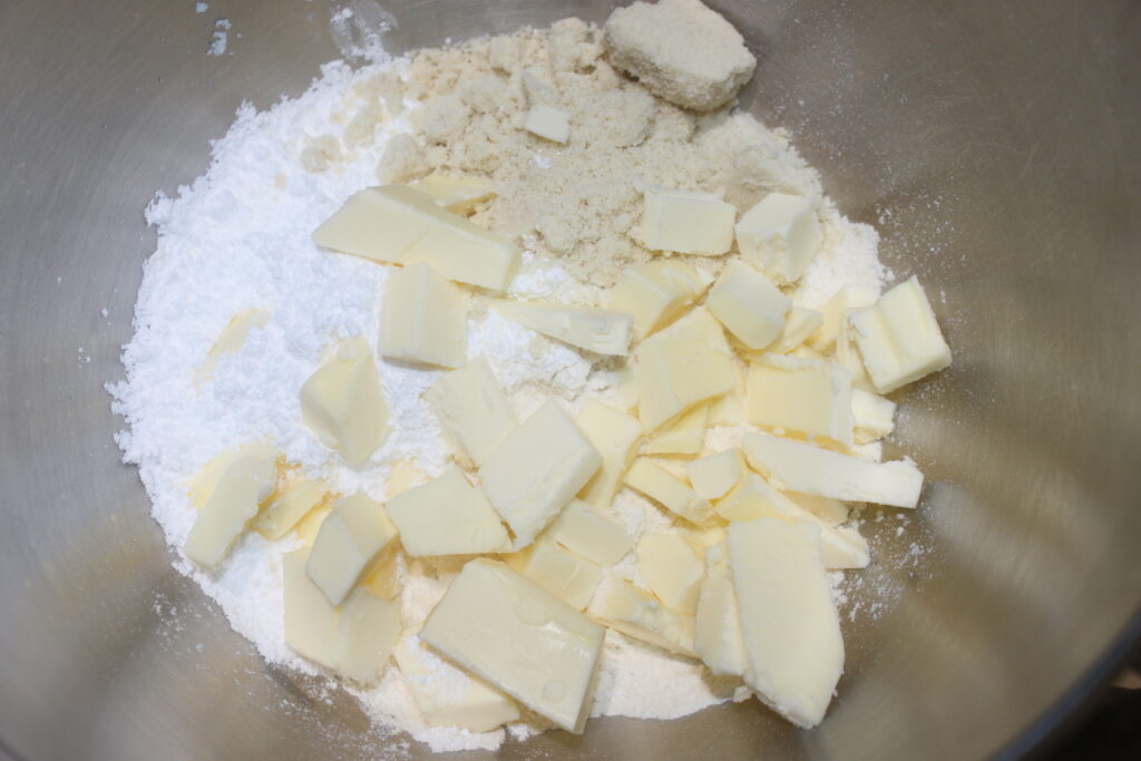 Mélangez les cubes de beurre avec la farine et le sucre dans un saladier pour créer la base parfaite pour les Tartelettes crème d'orange.