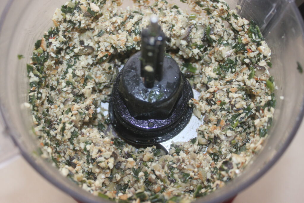 Les herbes hachées et les noix créent un mélange vibrant, parfait pour rehausser la saveur terreuse des shitakés dans le bol d'un robot culinaire.