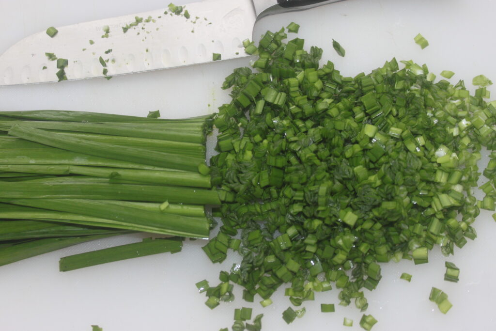 Des oignons verts hachés et des shiitakes finement tranchés sur une planche à découper avec un couteau créent la base parfaite pour les galettes de tofu.
