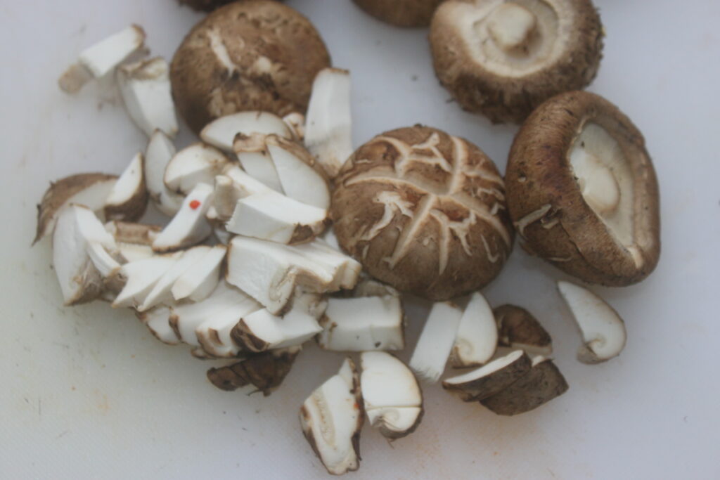 Les shitakés entiers et tranchés reposent élégamment sur une surface blanche.
