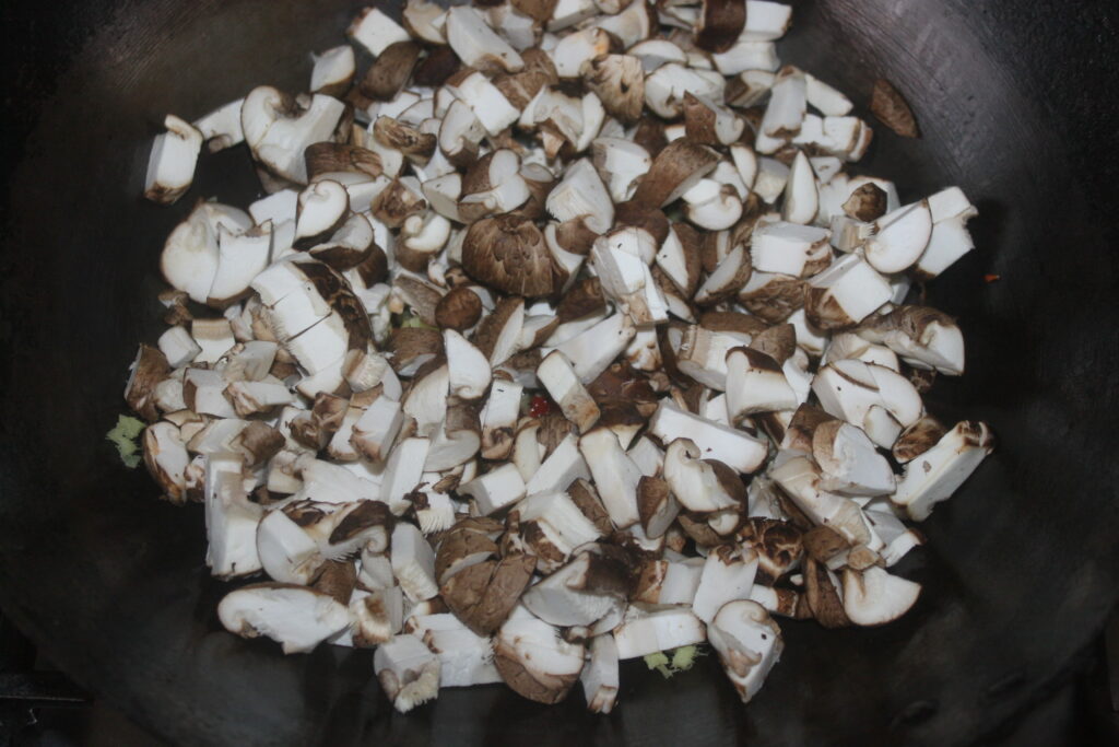 Les shitakés et les champignons hachés grésillent harmonieusement dans la poêle, créant un arôme délicieux.