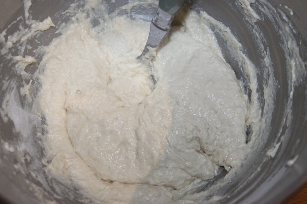 Un bol à mélanger rempli de pâte crémeuse et épaisse pour des galettes parfaites est remué avec un ustensile en métal.