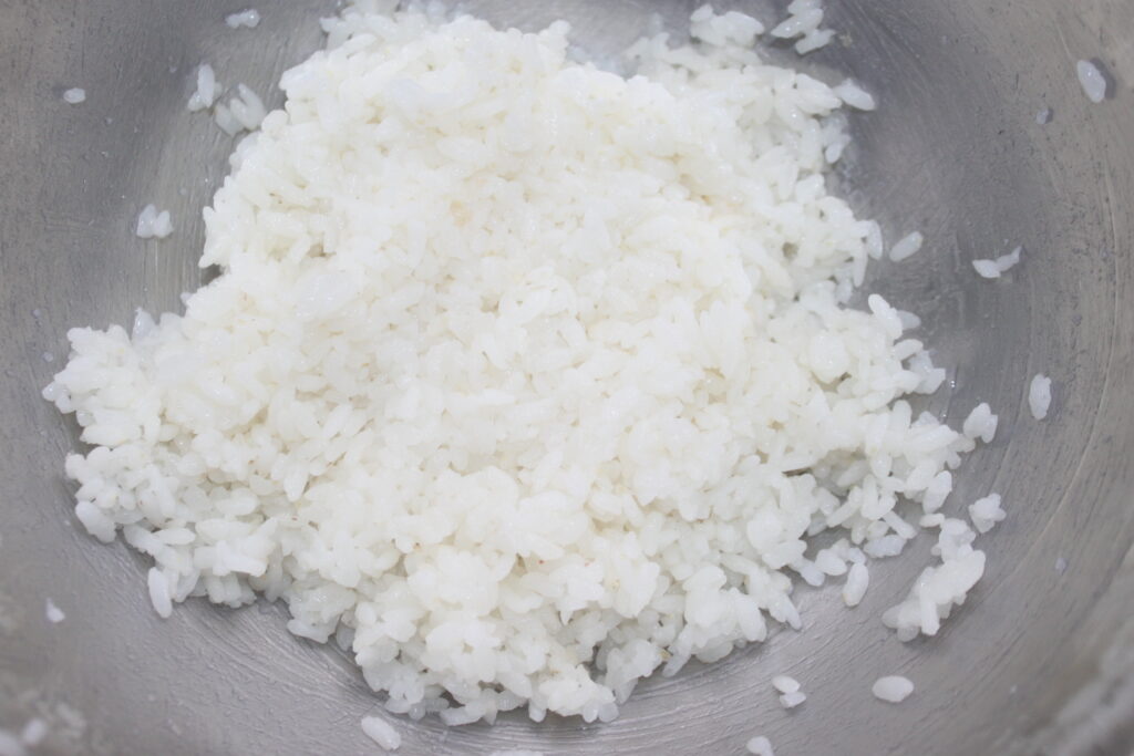 Gros plan du riz blanc dans un bol en acier inoxydable.