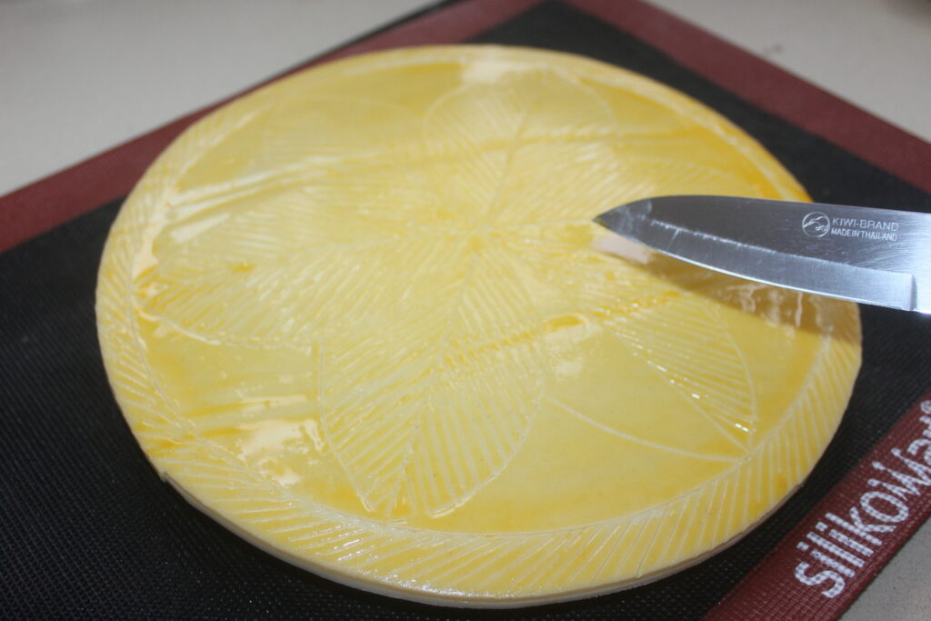 Un couteau tranchant un gros bloc jaune de beurre en couches, révélant de subtils tourbillons rappelant le caramel.