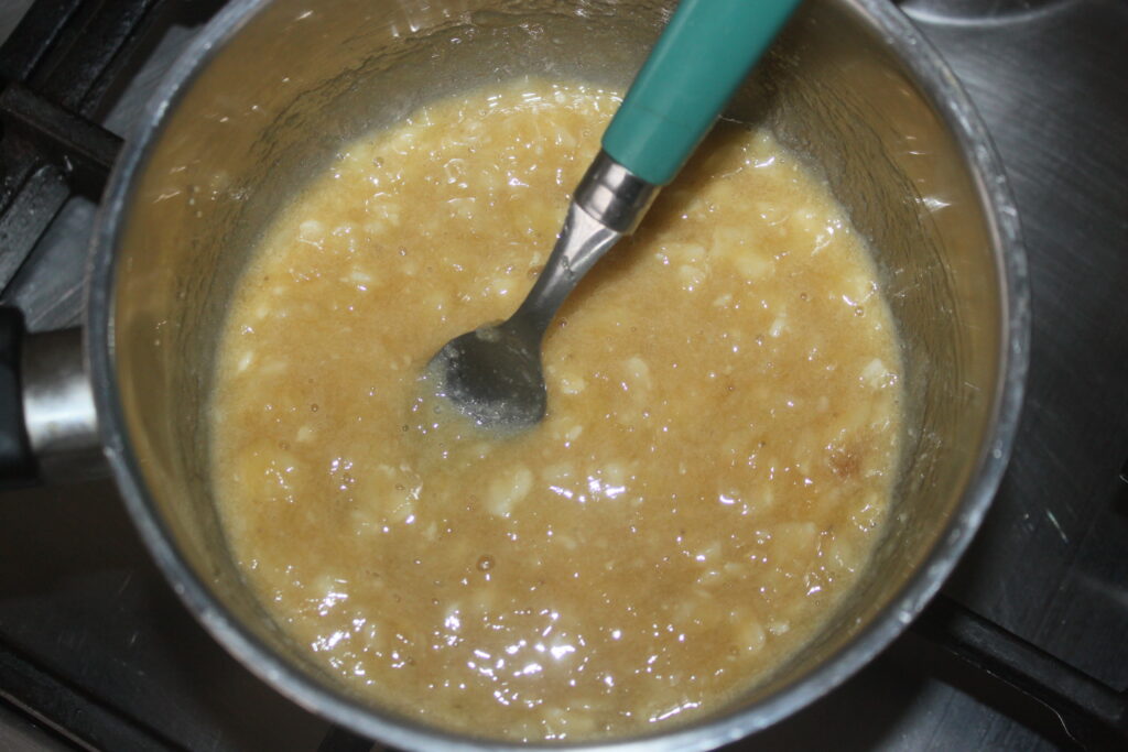 Un délicieux mélange de bananes écrasées, de cacahuètes et d'autres ingrédients dans une casserole, délicatement remué avec une cuillère.