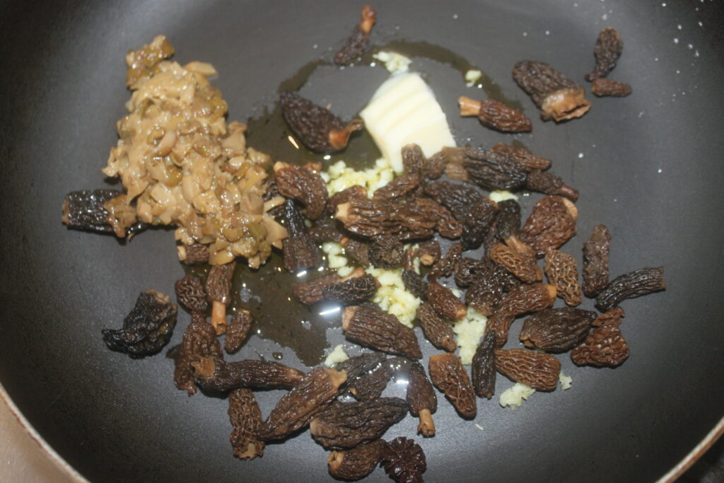 Des oignons hachés, des morilles et de l'ail grésillent dans une poêle avec une noix de beurre, créant un arôme rappelant les cèpes sautés dans la campagne française.