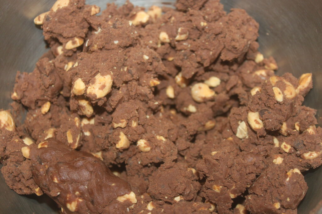 Gros plan d'un bol rempli d'une riche pâte au chocolat et au cacao mélangée à des morceaux d'amandes grillées.