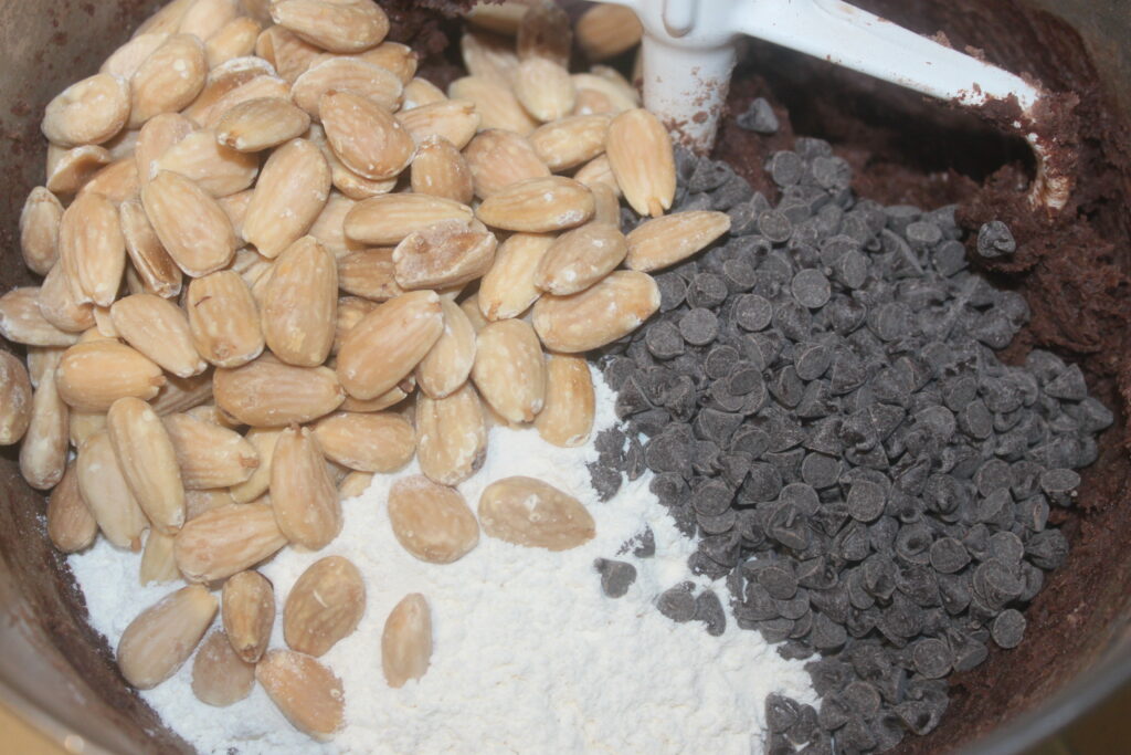 Un bol rempli de farine devient un délicieux mélange où les pépites de chocolat, la poudre de cacao et les amandes grillées se mélangent harmonieusement.