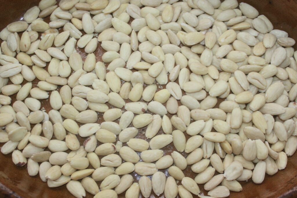 Gros plan sur des amandes blanchies réparties uniformément, prêtes à être transformées en sablés délicats.