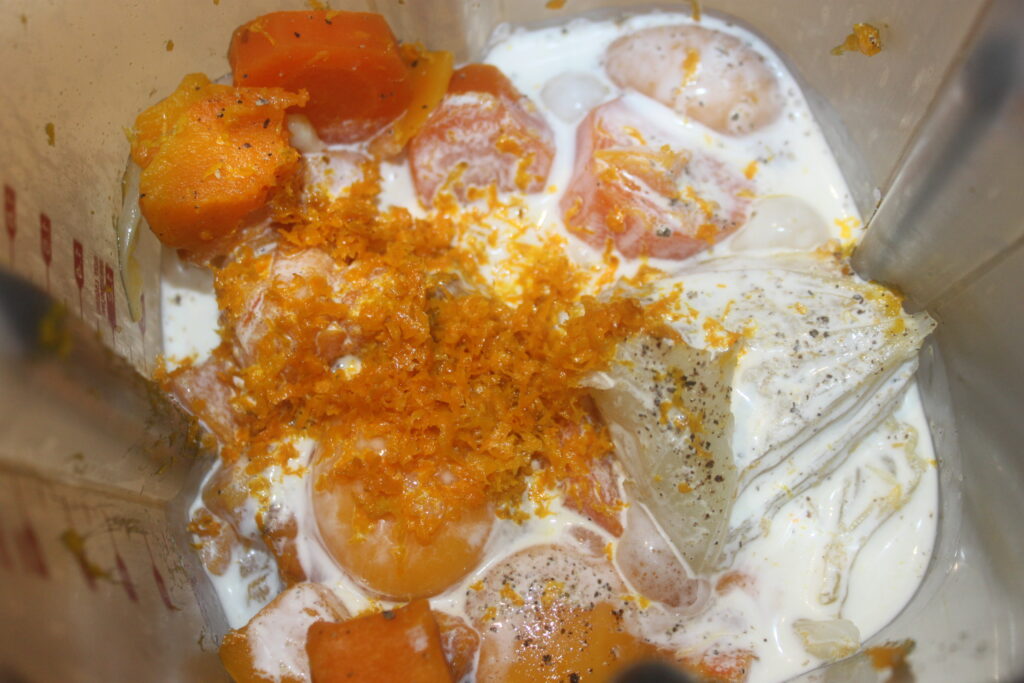 Les ingrédients dans un mélangeur, y compris le zeste d'orange, le lait, les morceaux de patate douce et la glace, créent une saveur rappelant le beurre à l'orange.