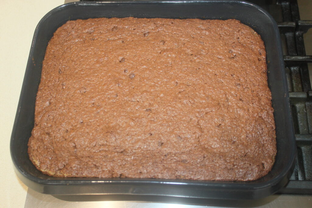 Un brownie au chocolat fraîchement cuit dans un moule carré noir sur la cuisinière, rappelant un gâteau décadent.
