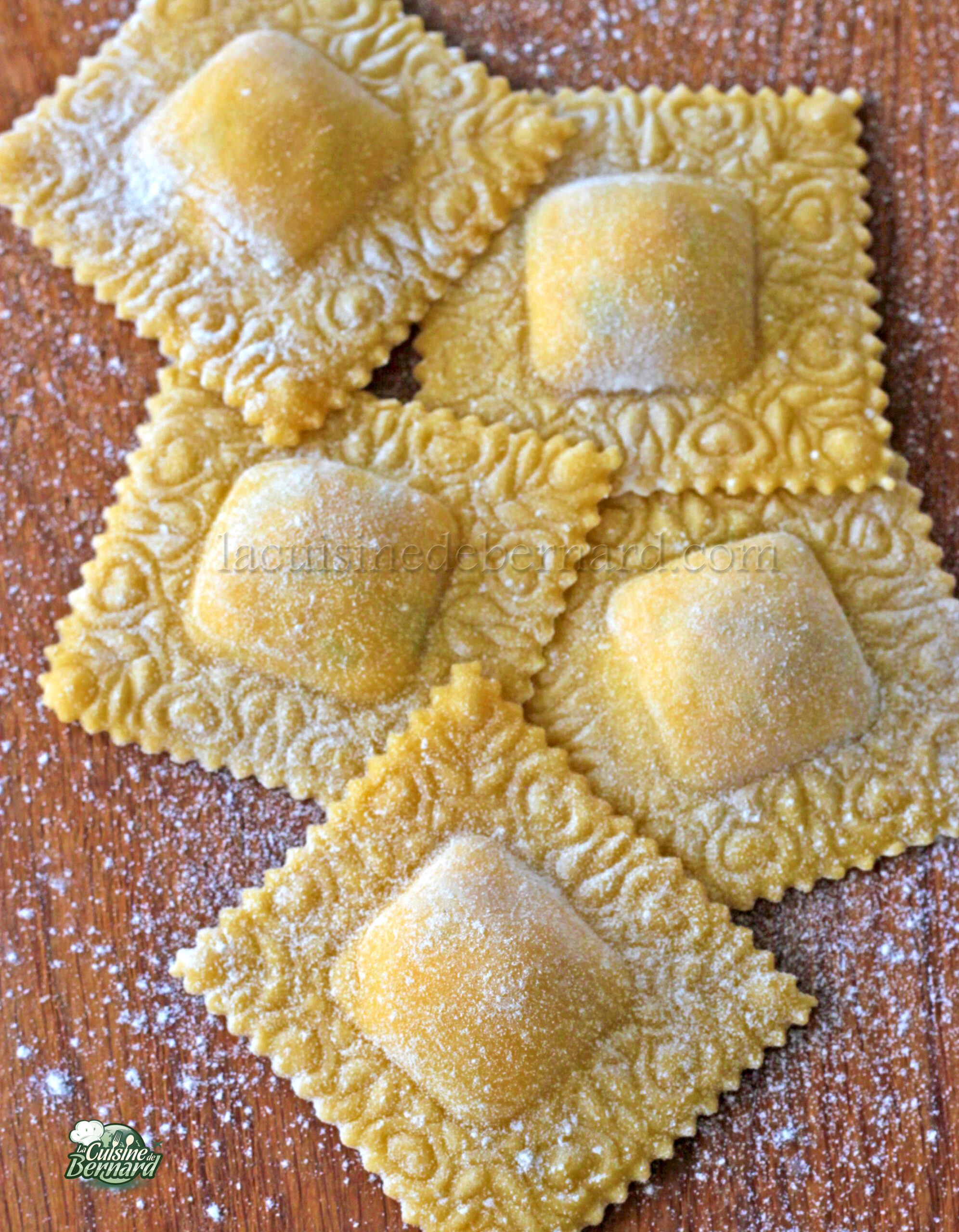 Cinq morceaux de raviolis crus saupoudrés de farine reposent élégamment sur une surface en bois, leurs poches délicates laissant deviner la garniture crémeuse de ricotta et de saumon à l'intérieur.