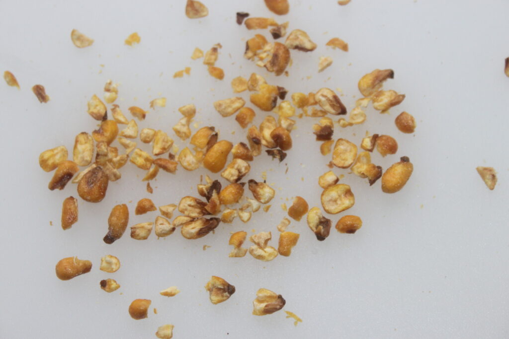 Gros plan de grains de maïs hachés et dispersés sur une surface blanche, rappelant les ingrédients d'un ceviche vibrant.