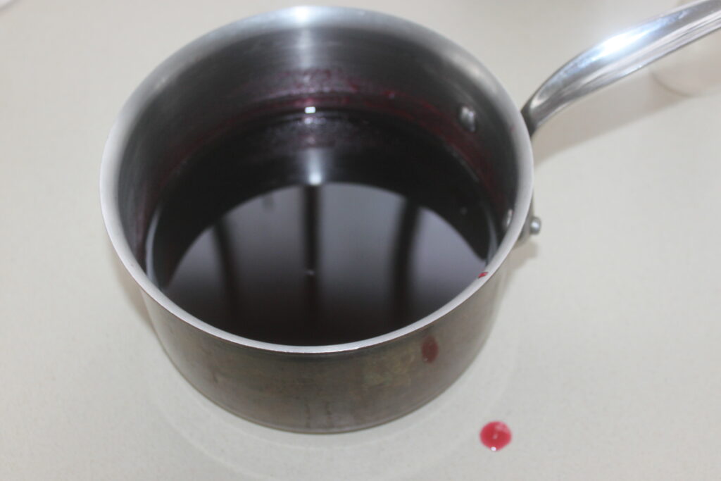 Une casserole en métal remplie d'un liquide sombre, avec un peu renversé sur le côté, rappelant un spritz de plage rafraîchissant.