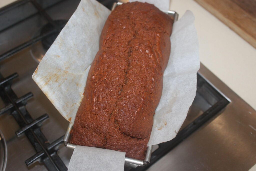 Une miche de pain cuite dans un moule en métal recouvert de papier sulfurisé, posée sur une cuisinière.